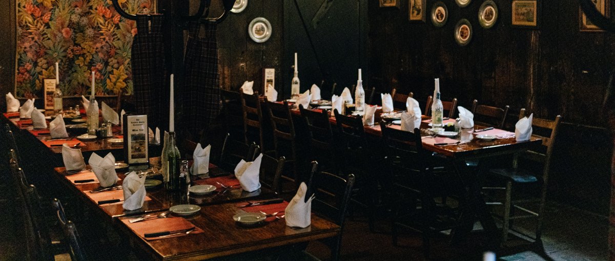 Interior of restaurant's dark dining with tables set and wall lamps lit