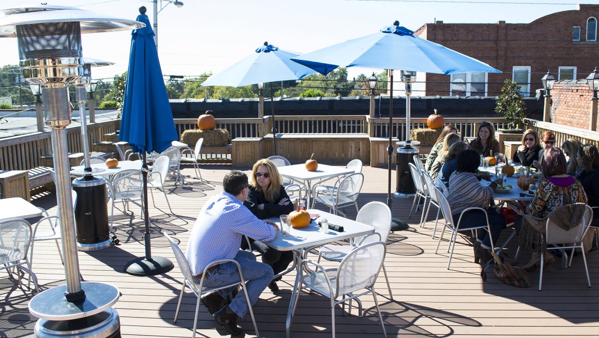 People sitting at tables on restaurant rooftop during daytime