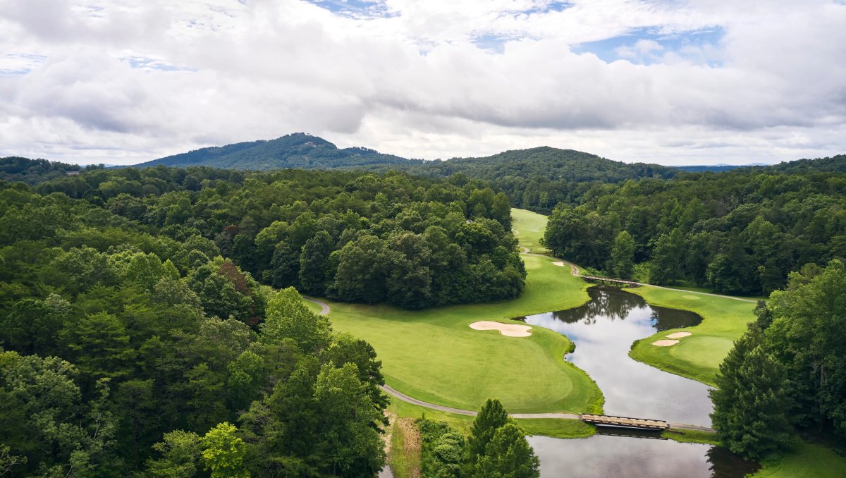 Aerial of green golf course with mountains in background