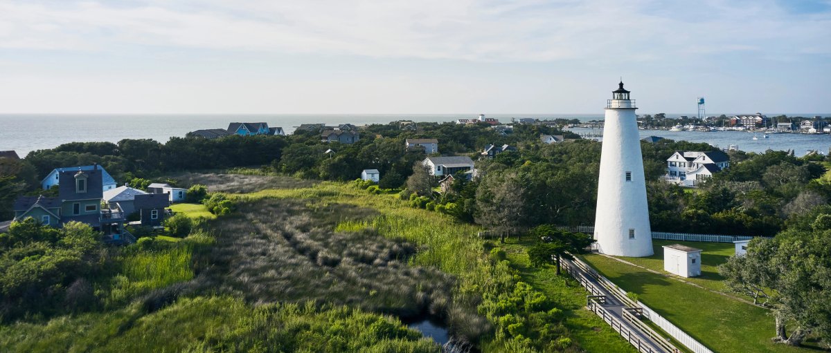 Aerial view of Ocracoke Lighthouse and green marshes and houses surrounding it