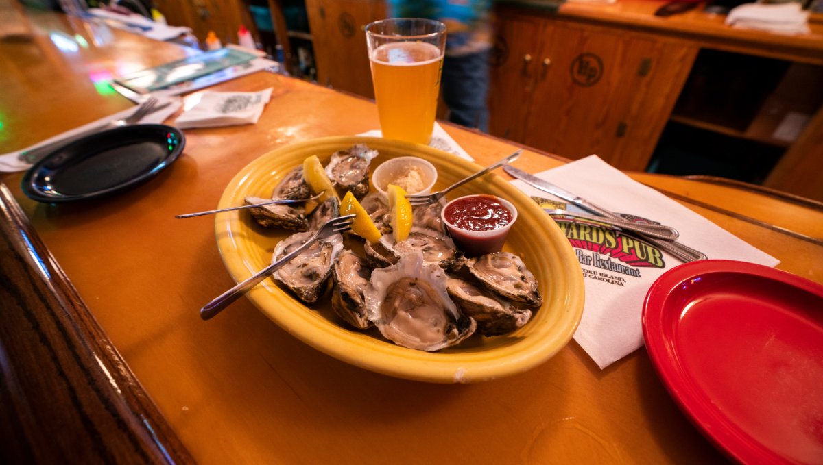 Plate of oysters and a beer sitting on a bar