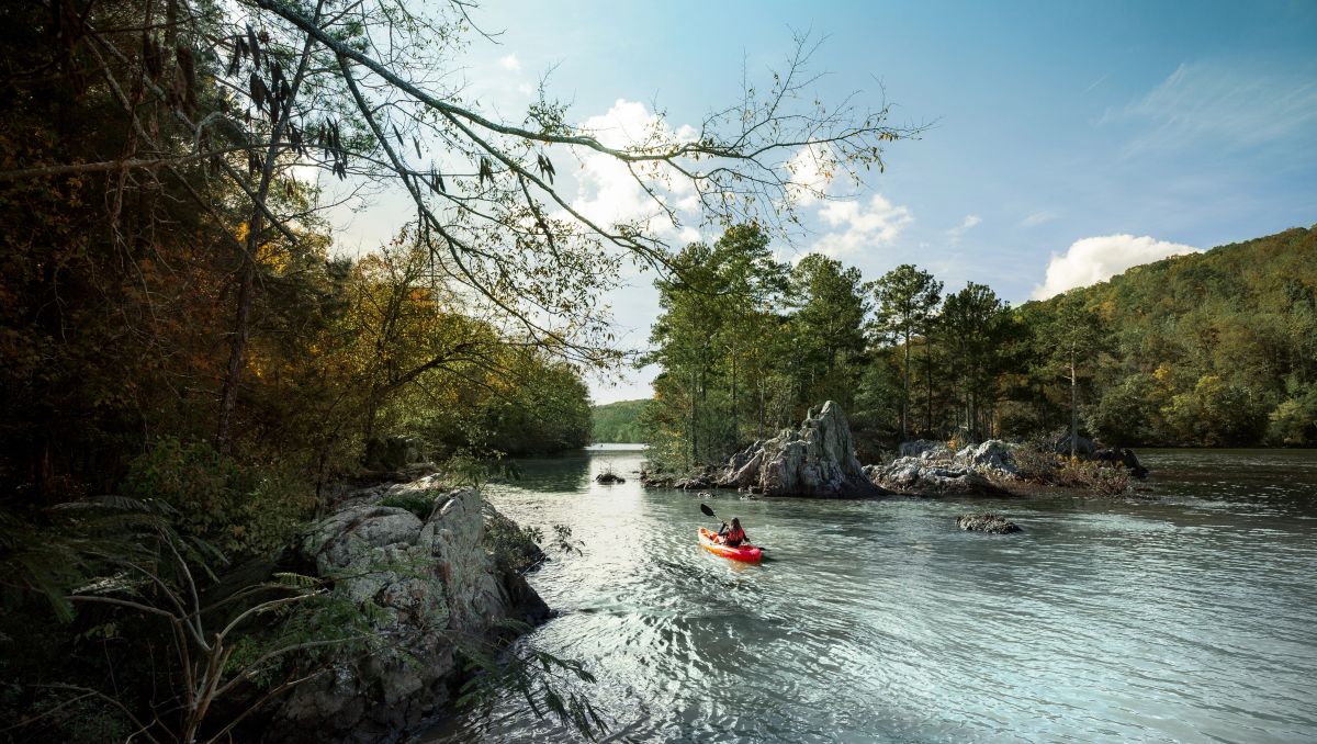 Kayaker in distance on Badin Lake with island of trees and rocks in the middle during daytime