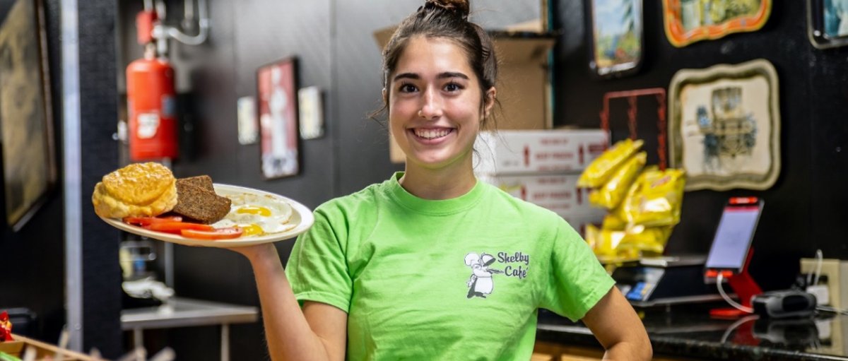 Woman holding  plate of breakfast food and smiling for camera