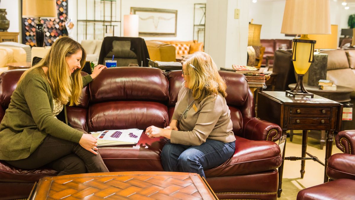 Two women sitting on couch while shopping for furniture at Hickory Furniture Mart