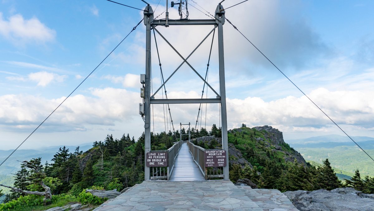 Swinging bridge at top of mountain view down walkway to other peak