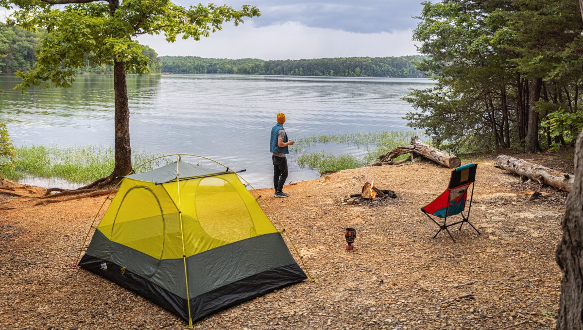 Man standing outside tent, gazing out over Badin Lake in Uwharrie National Forest, North Carolina.