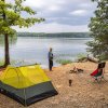 Man standing outside tent, gazing out over Badin Lake in Uwharrie National Forest, North Carolina.