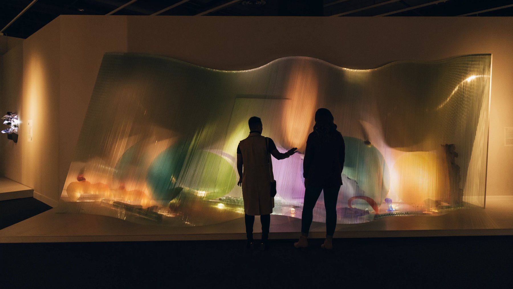 Two people standing in front of large art display in museum