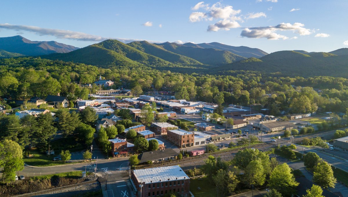 Aerial of small mountain town with trees and Blue Ridge Mountains in background