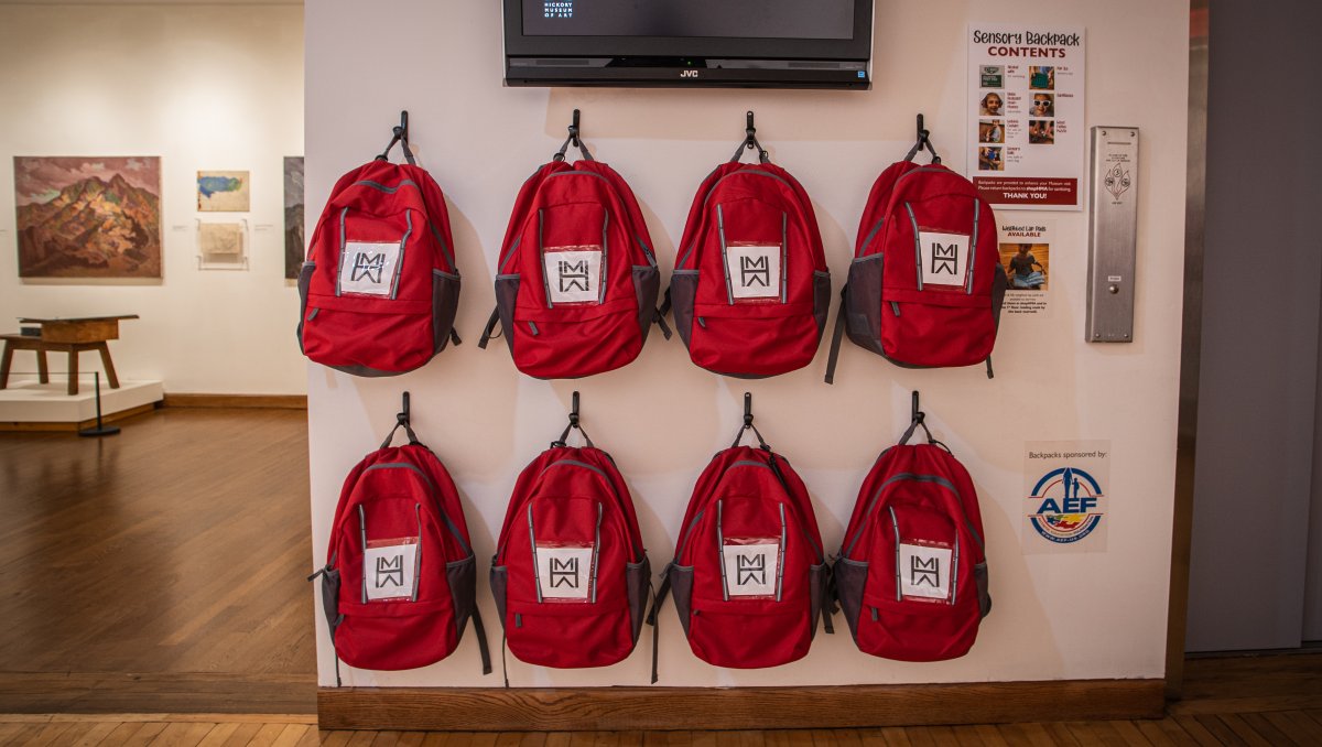 Wall of red sensory backpacks for visitors at art museum
