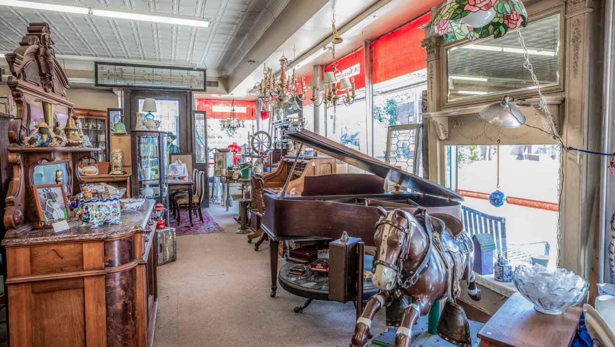 Interior of antique mall with tons of furniture, toys and lighting.