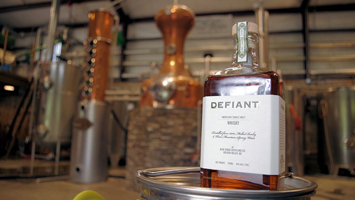 Closeup of bottle of whisky at Blue Ridge Distilling Company with equipment in background