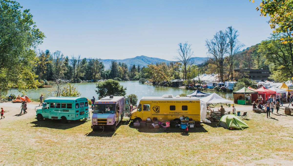 Colorful trucks parked by lake at LEAF Festival in Black Mountain on sunny day 