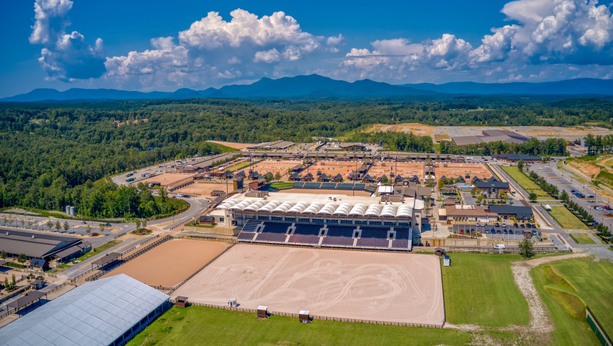 Aerial view of sprawling Tryon International Equestrian Center complex with mountains in background during daytime