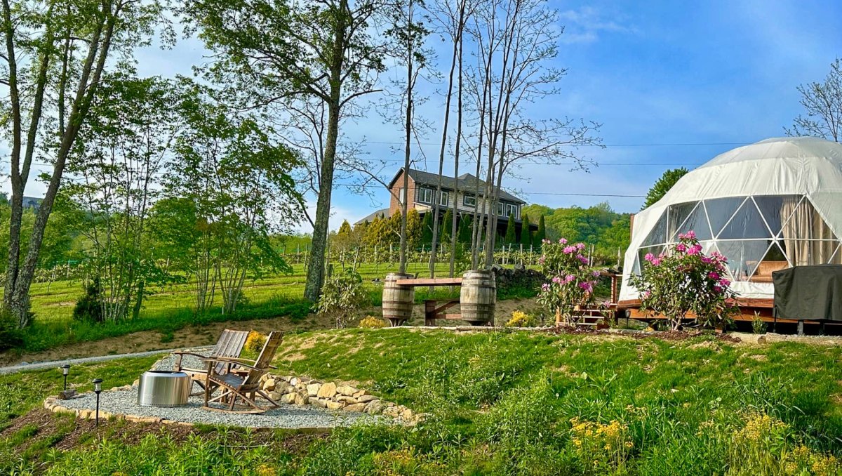 Exterior of glamping dome, porch and fire pit in mountain getaway during daytime.