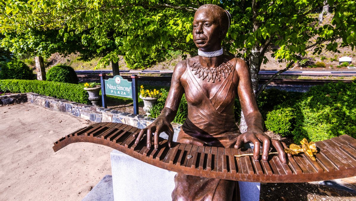 Closeup of bronze Nina Simone statue with green trees in background during daytime