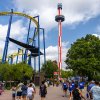 People walking around Carowinds amusement park with rides and roller coasters in background.