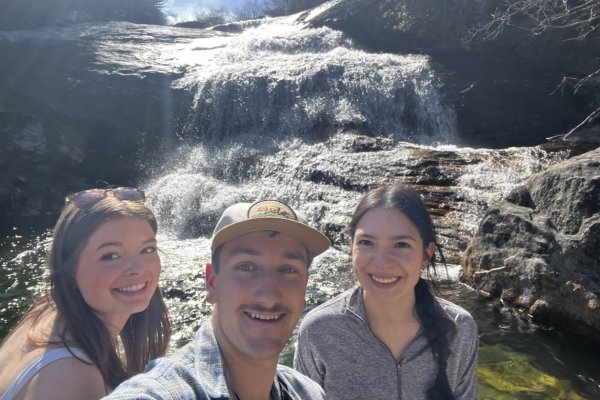 Two girls and a guy taking a selfie in front of a waterfall 