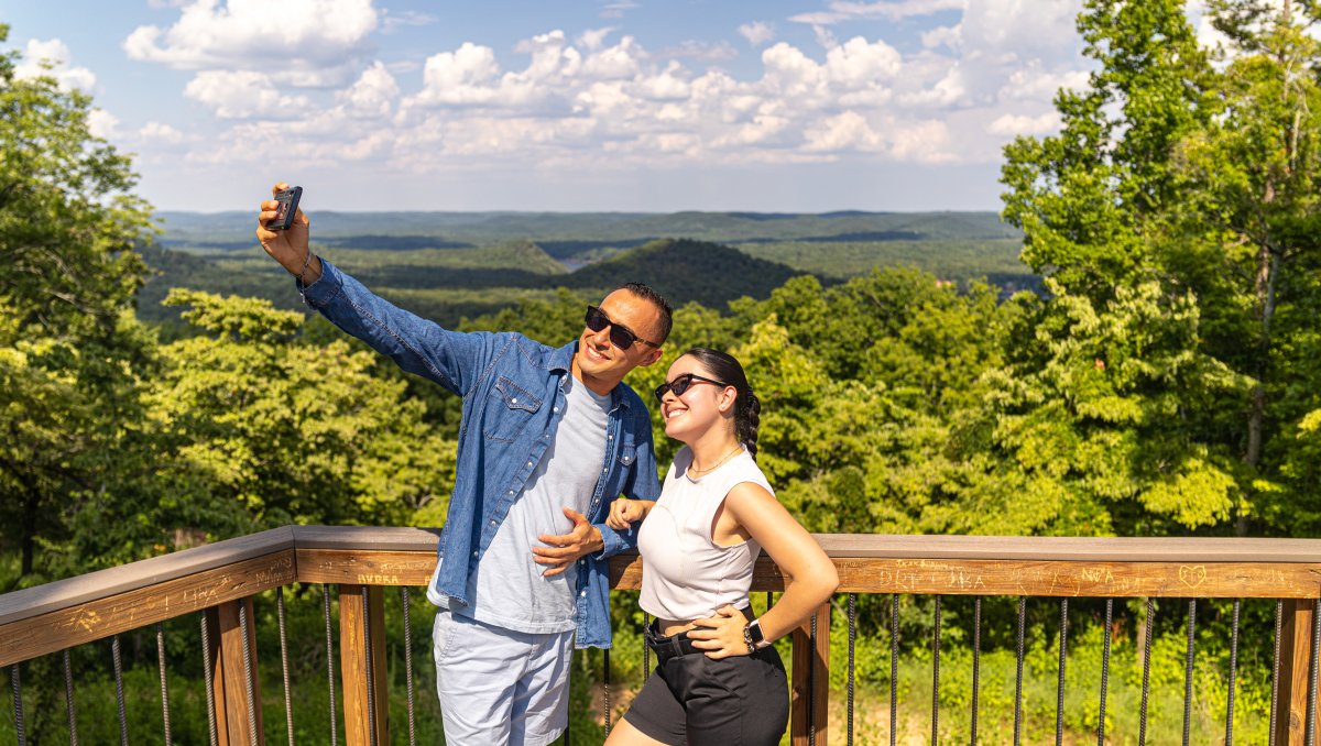 Couple taking a selfie at overlook in Morrow Mountain State Park with mountains in background.