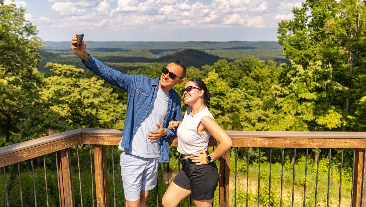 Couple taking a selfie at overlook in Morrow Mountain State Park with mountains in background.