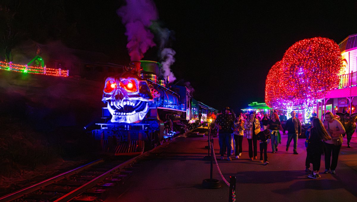 Visitors to Tweetsie Railroad's Ghost Train walking outside of train surrounded by Halloween decorations.