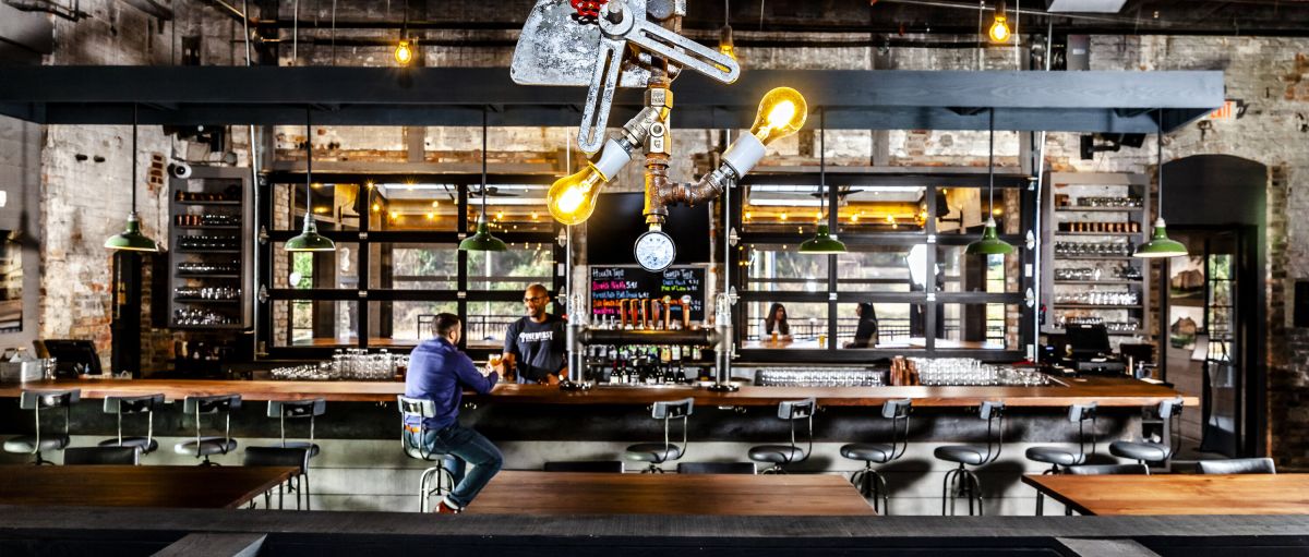 Man sitting at bar by himself talking to bartender inside Pinehurst Brewing Company