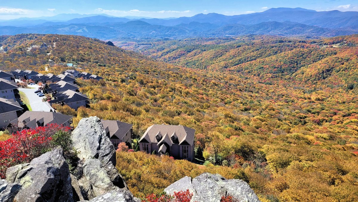 Aerial view of vacation rentals surrounded by bright fall foliage and mountains in background