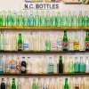 Shelves of antique soda bottles on display at antique store.