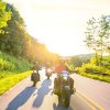 Three motorcyclists driving on mountain road during sunny day.