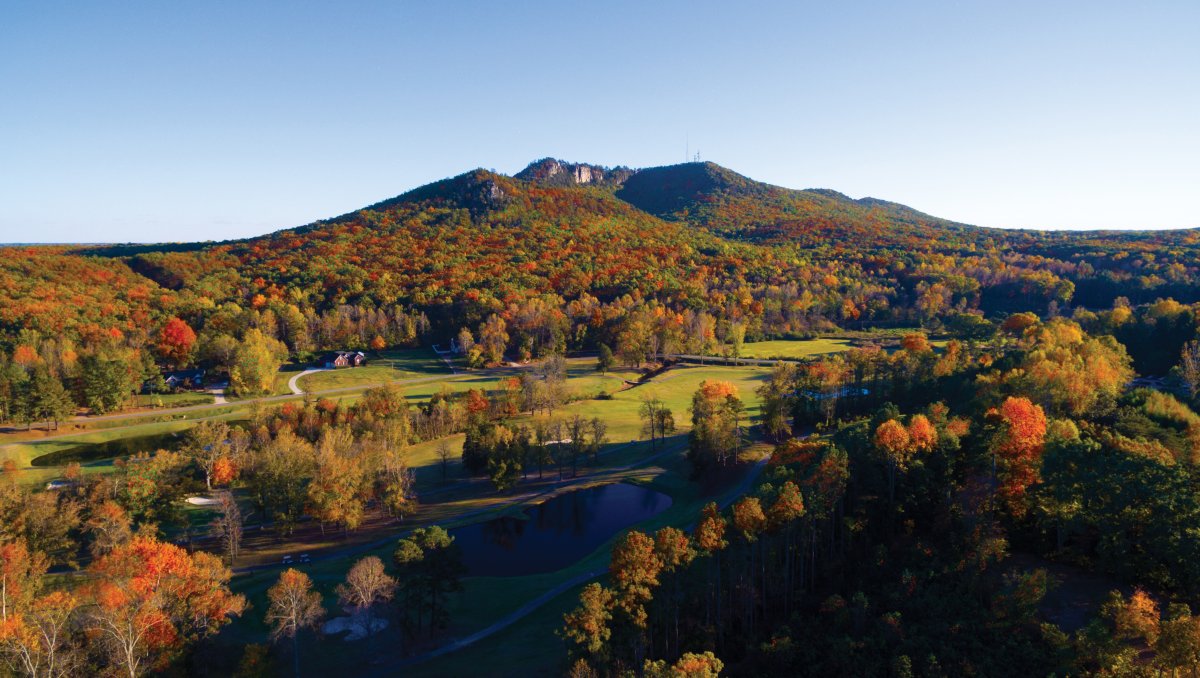 Aerial of Crowders Mountain Golf Course with mountain rising in distance during fall.