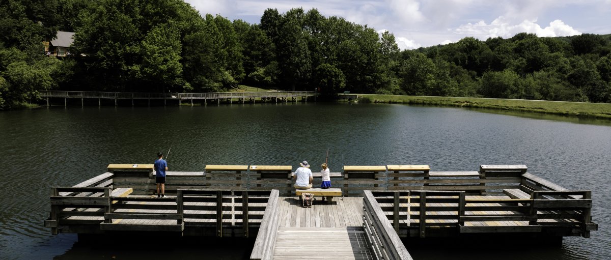 People fishing off large wooden fishing pier into Lake Coffey with trees in background.