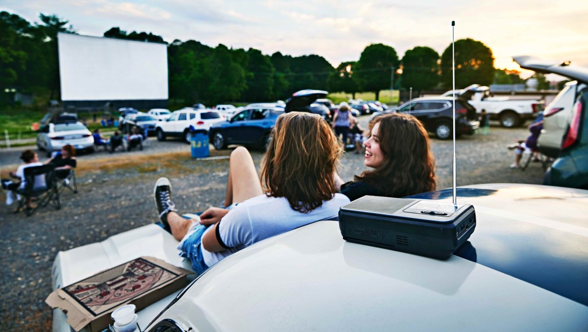 Two friends sitting on hood of the car waiting for drive-in movie to start