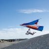 Person hang gliding over sand dunes during daytime