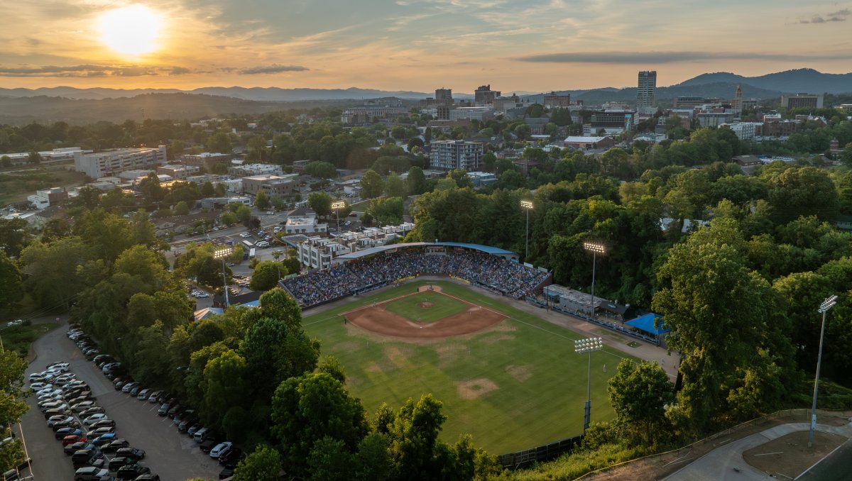 Aerial of McCormick Field at sunset in downtown Asheville with mountains in background.