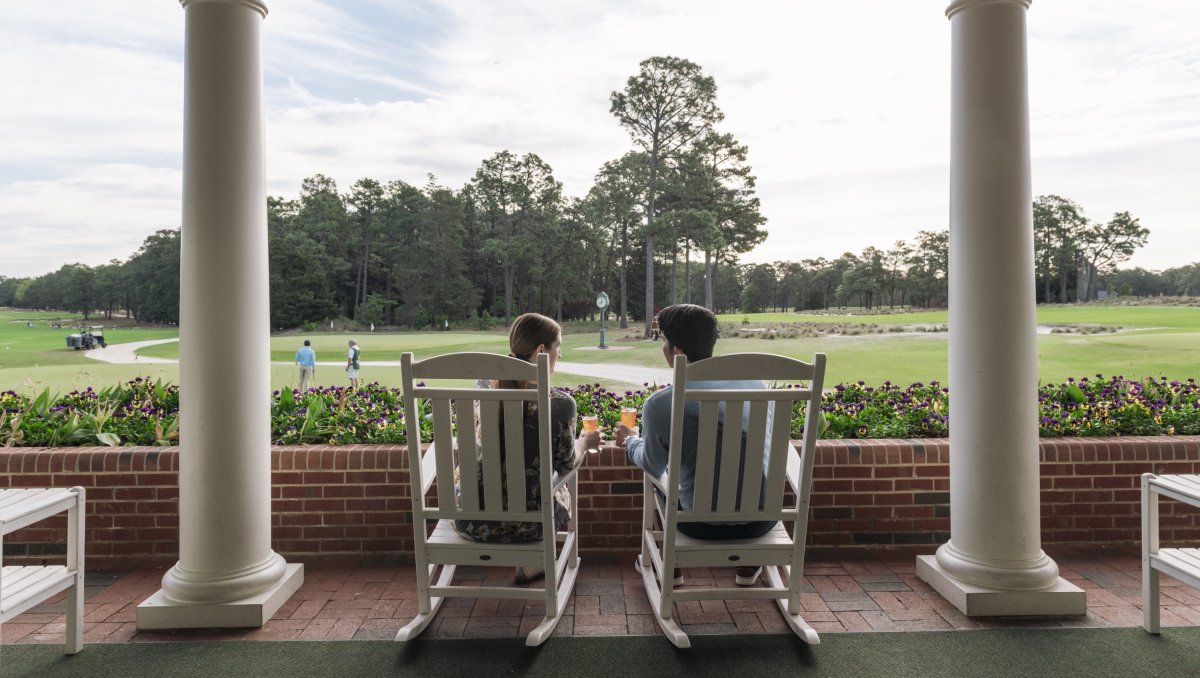 Back of couple sitting in rocking chairs overlooking golf course