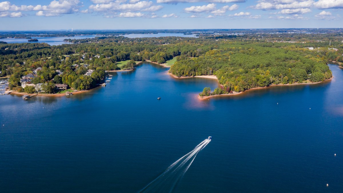 Aerial of boat on Lake Norman with shore and land in distance.