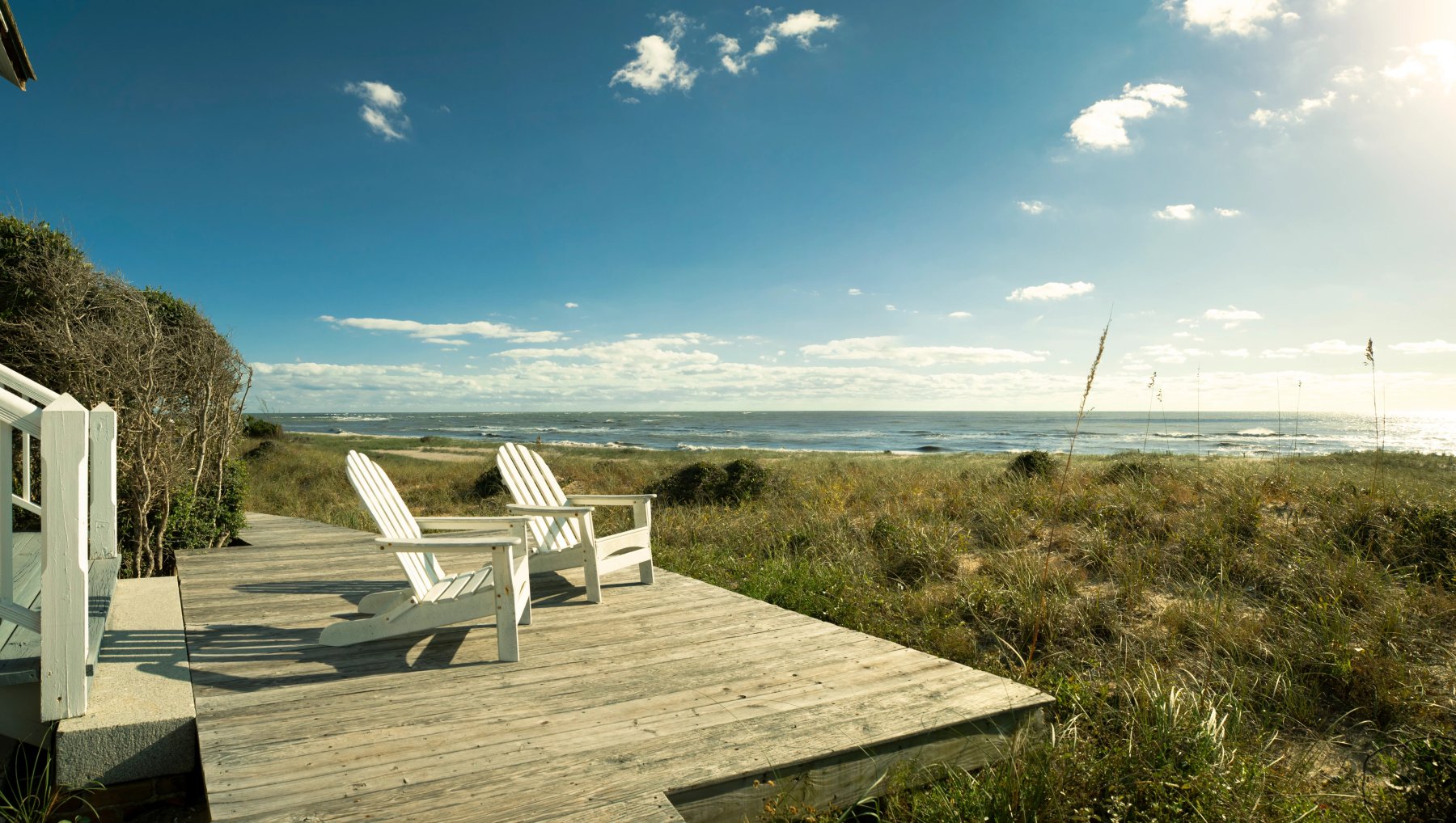Two Adirondack chairs sitting on wood platform in Bald Head Island marsh.