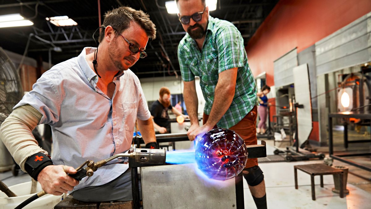 Craftsman working on glass art in workshop.