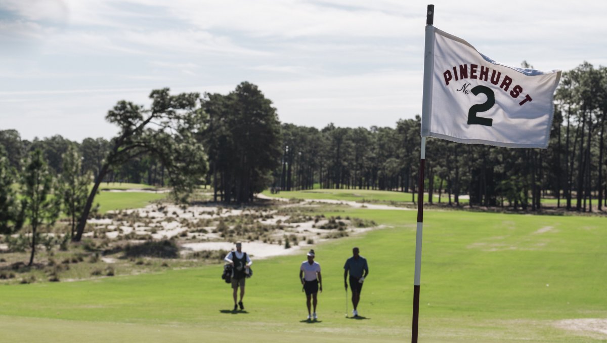 Pinehurst No. 2 flag in foreground with golfers and course in background