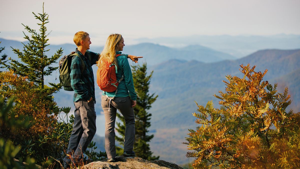 Couple gazing off into mountains with man pointing at something unseen