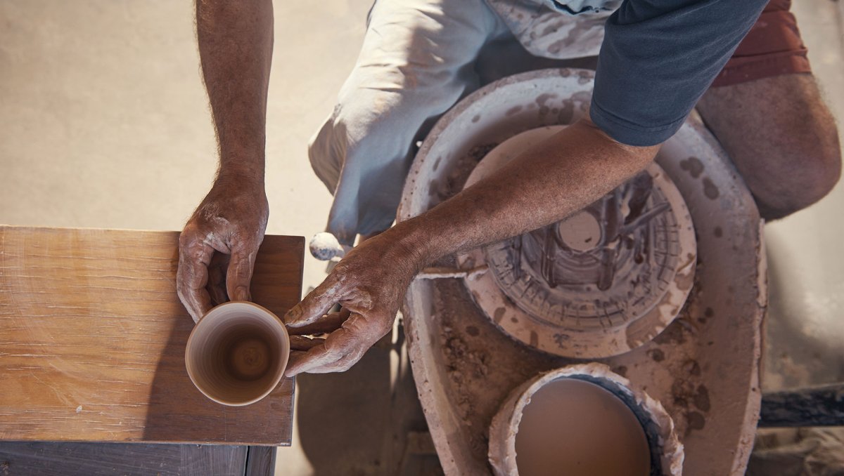 Overhead of person working with pottery at wheel.