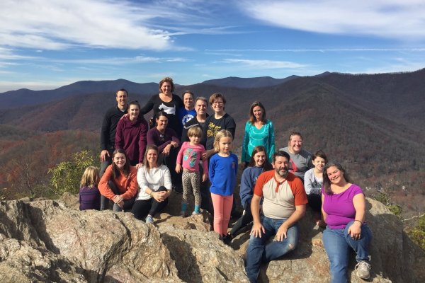Large family posing for photo at peak of mountain with mountains in background