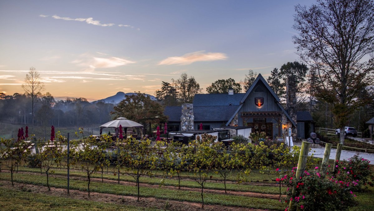 Exterior of JOLO Winery & Vineyards at dusk with Pilot Mountain visible in background