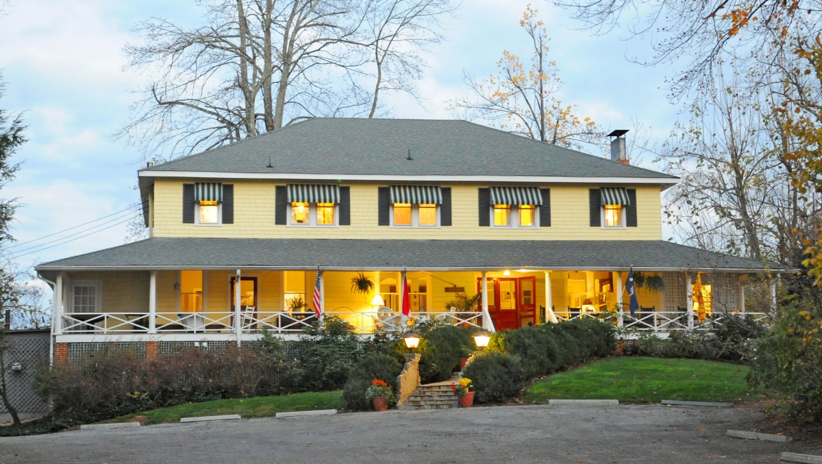 Exterior of yellow two-story inn with empty parking lot in front during cloudy daytime