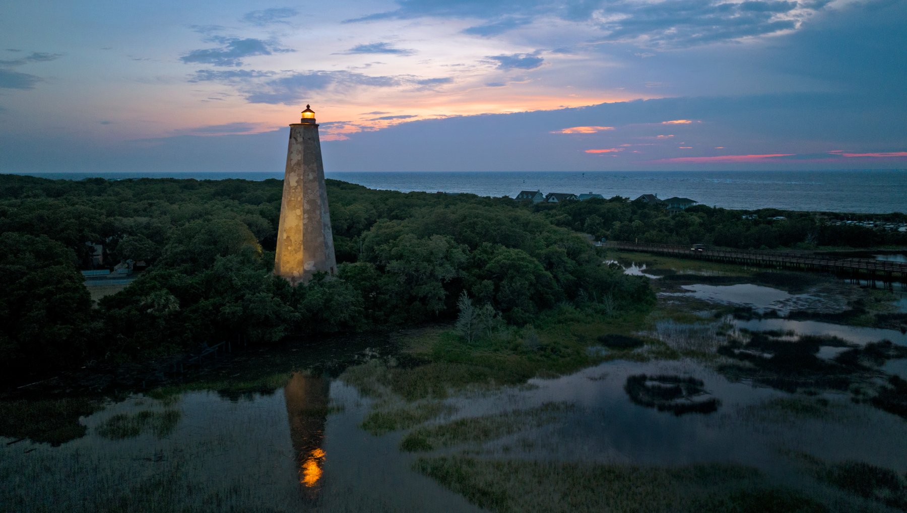 Aerial of Old Baldy lighthouse and surrounding grounds and marshes at sunset.