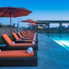Long row of orange lounge chairs sitting by pool at dusk