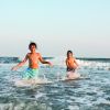 Two smiling boys splashing through waves in Ocean Isle Beach in the Brunswick Islands