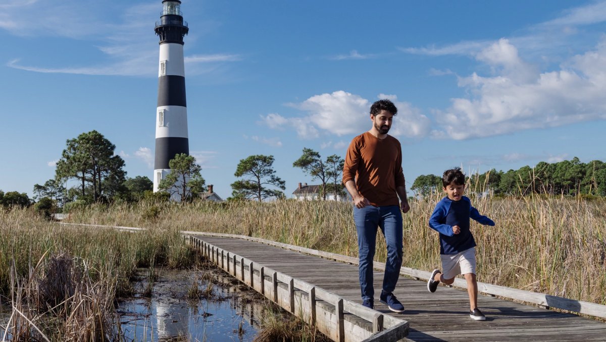 Father and son walking on path through marsh with black and white behind them 