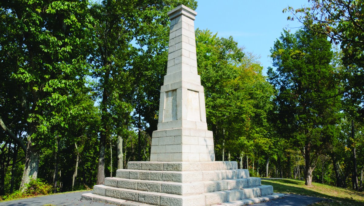 Large Kings Mountain Monument surrounded by trees and a walking path.