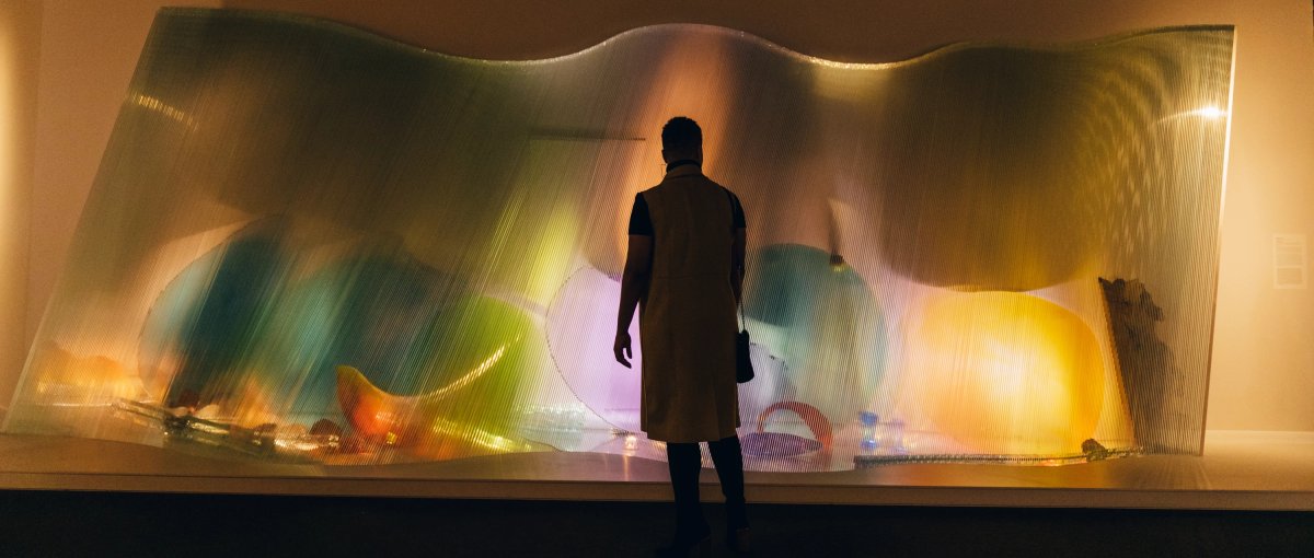 Silhouette of woman admiring colorful sculpture in art museum